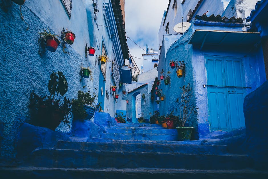 Colorful pots line the blue-washed walls of a narrow alley in Chefchaouen, Morocco.