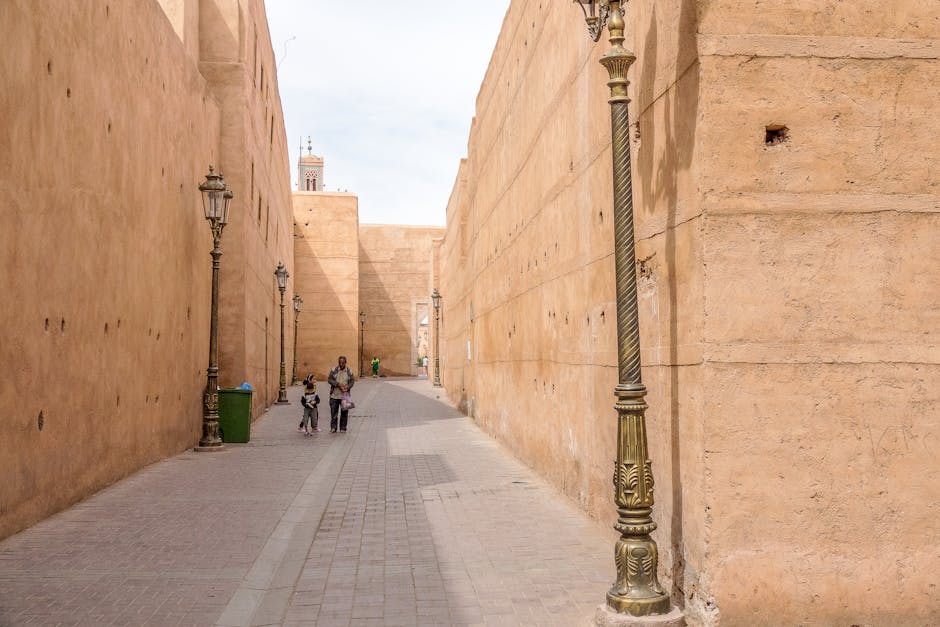 Old city alley with tall stone walls and traditional lamps, showcasing historic architecture.